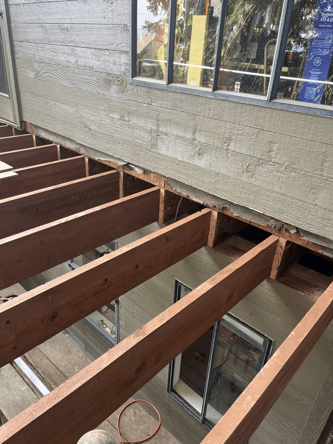 Deck framing with joists spanning between beams beside the house