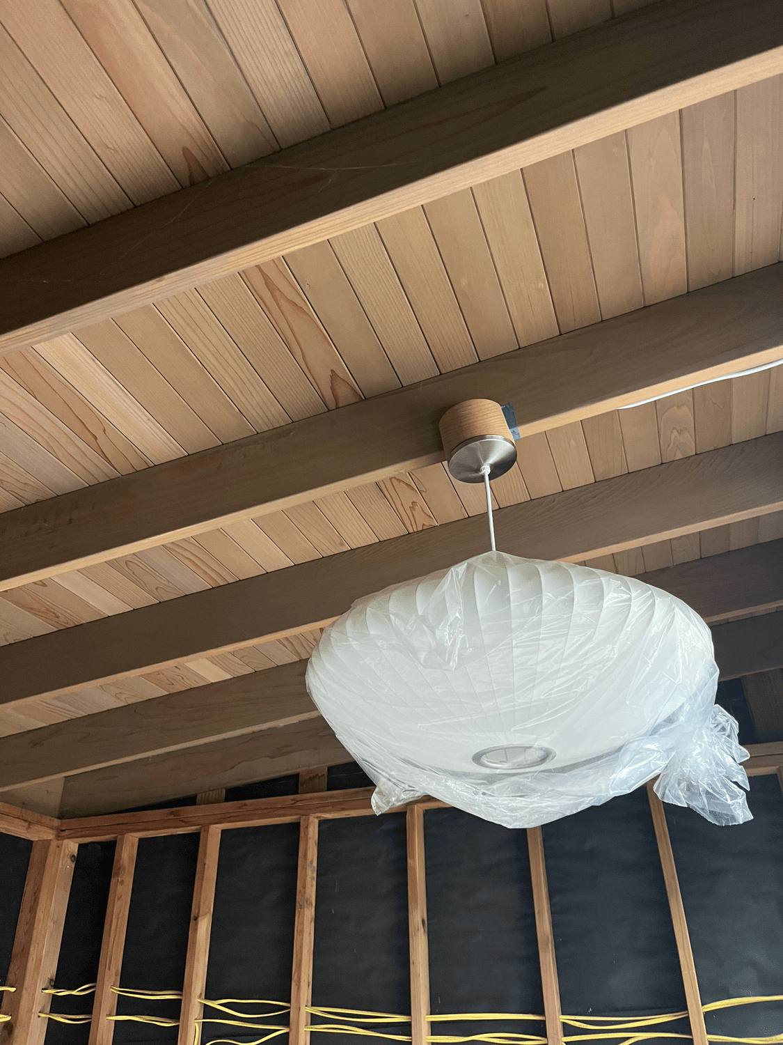 Ceiling light fixture being installed under a wood soffit