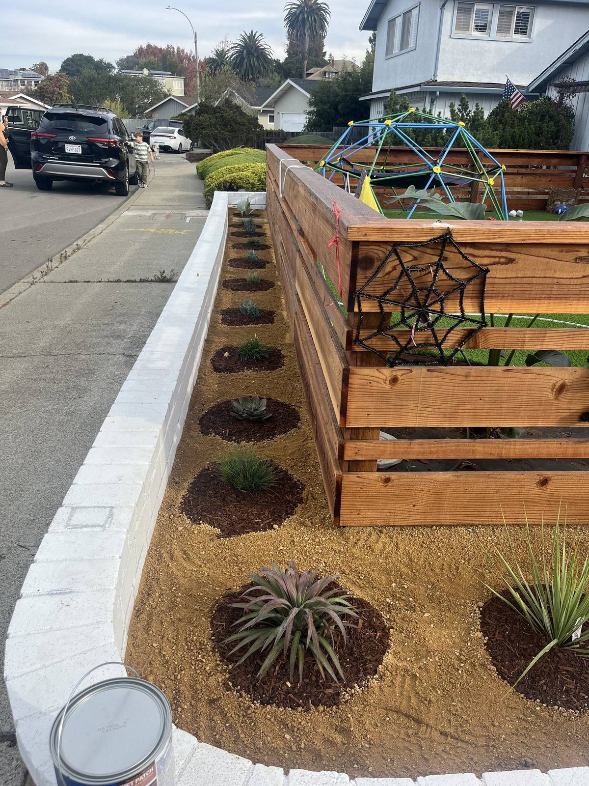 Fence and raised planter beds along a front sidewalk