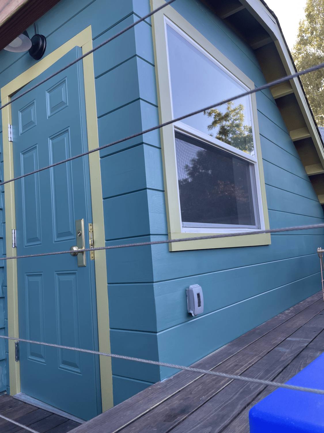 Outbuilding painted in blue with contrasting trim around the door and window