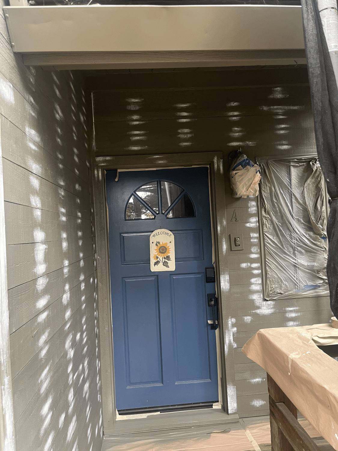 Entry door painted navy with the surrounding area masked and protected