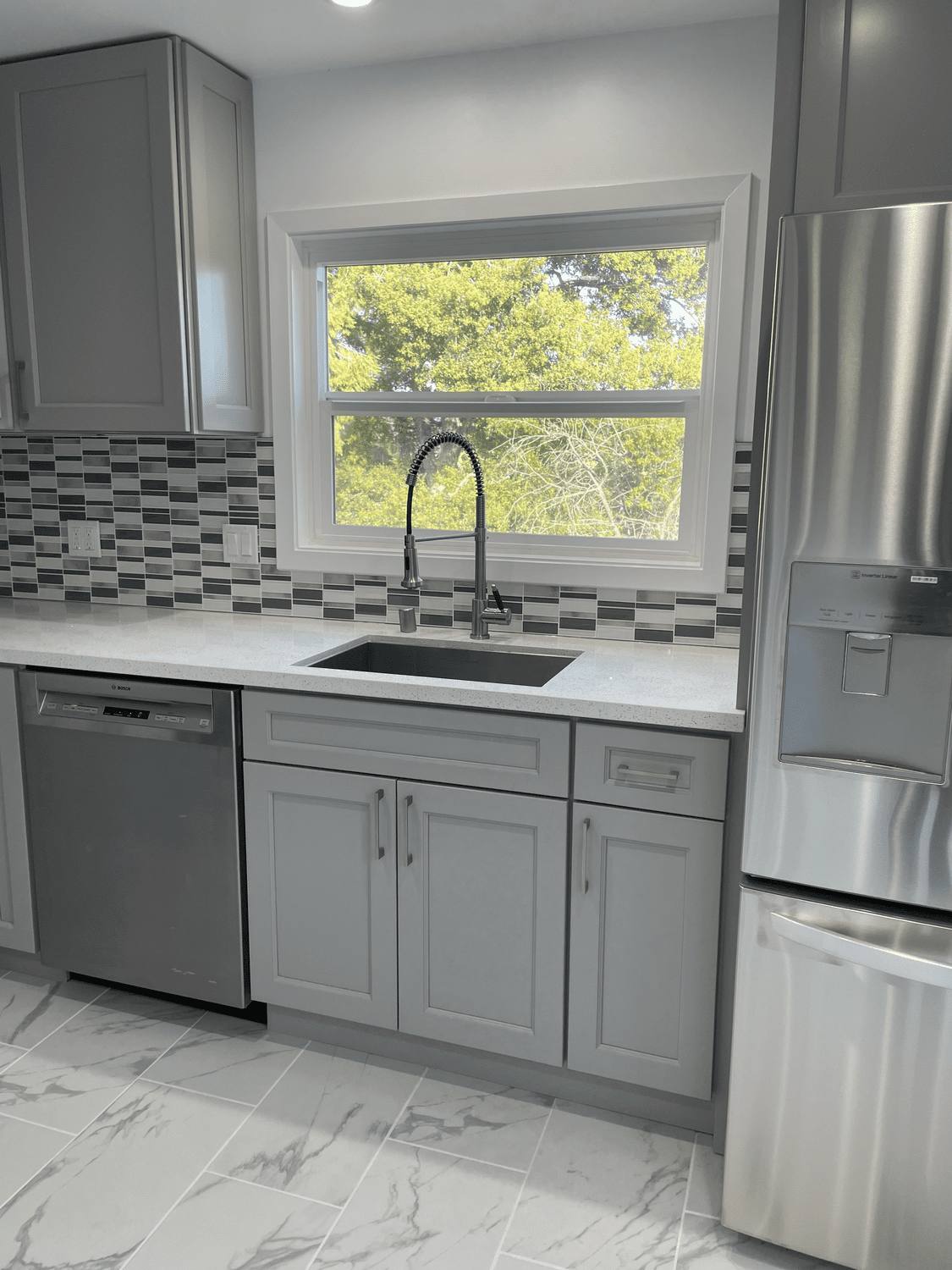 Kitchen sink under a window with new cabinets and countertop