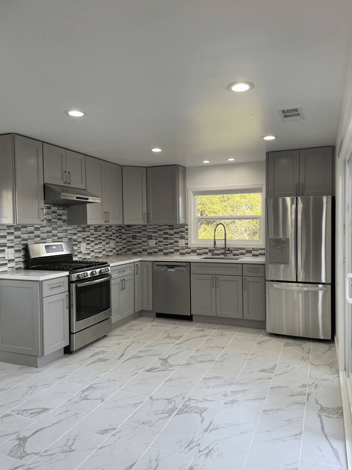 Finished kitchen remodel with gray shaker cabinets, tile backsplash and stainless appliances