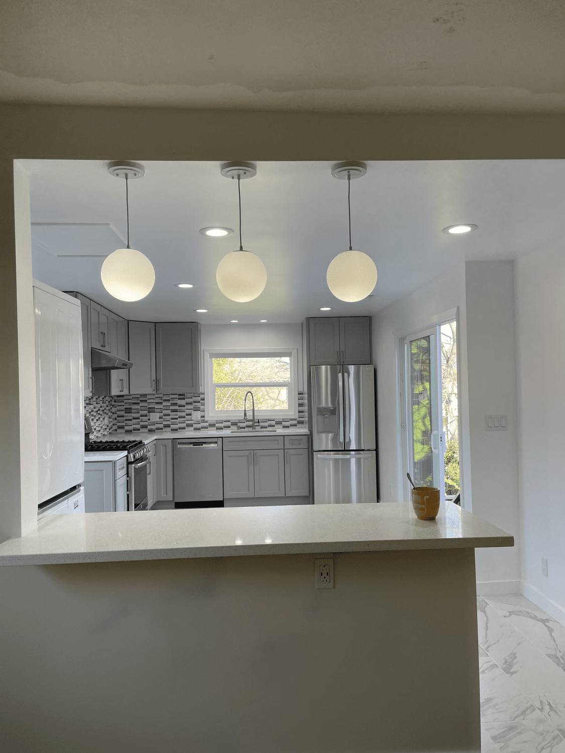 Remodeled kitchen with pendant lights and a stone peninsula