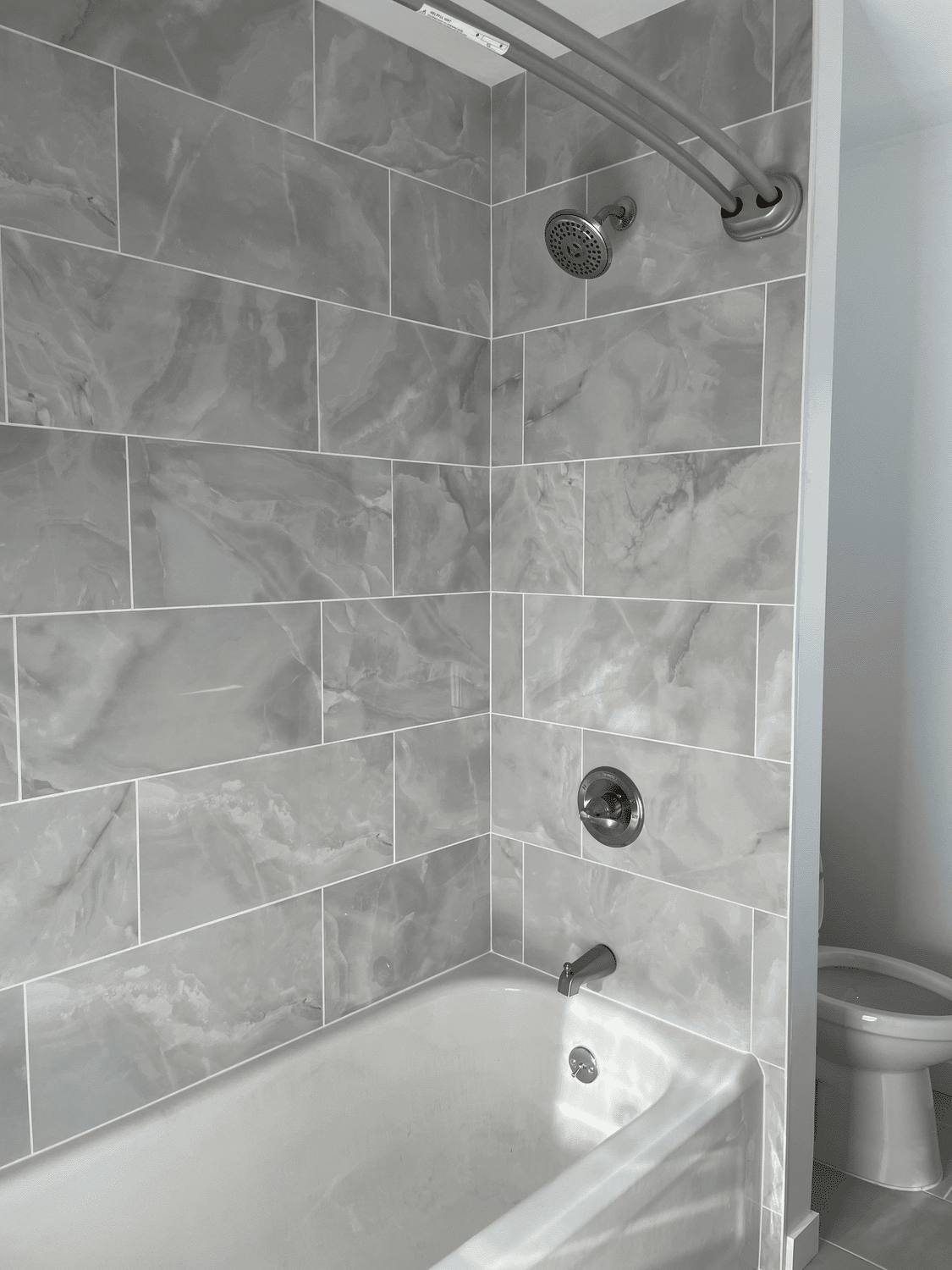 Tub and shower surround tiled in large-format marble-look tile