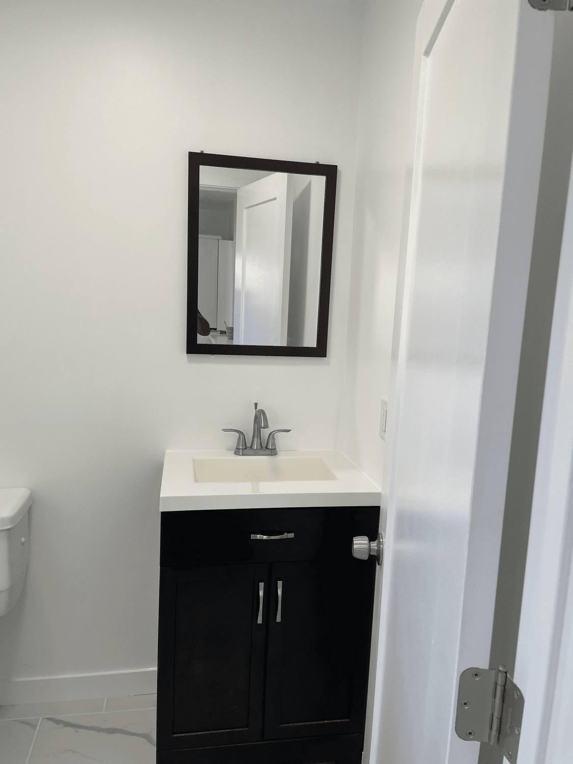 Remodeled bathroom with dark vanity, framed mirror and new fixtures