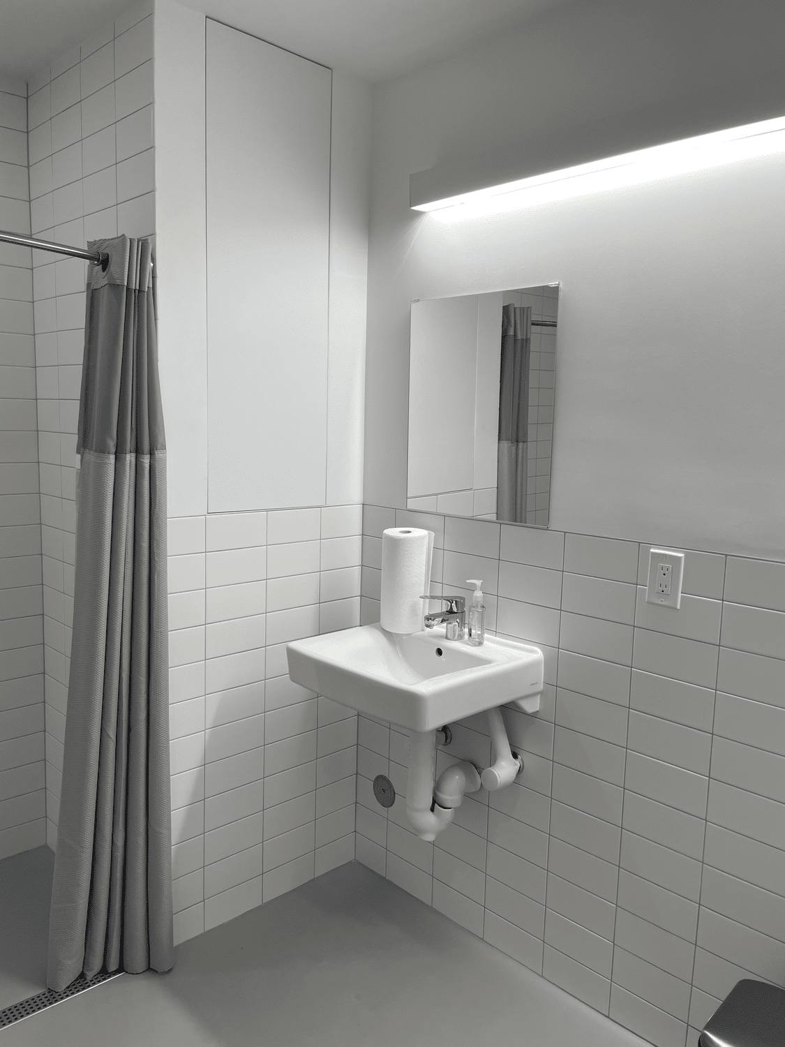 Compact bathroom with white tile walls and a wall-mounted sink